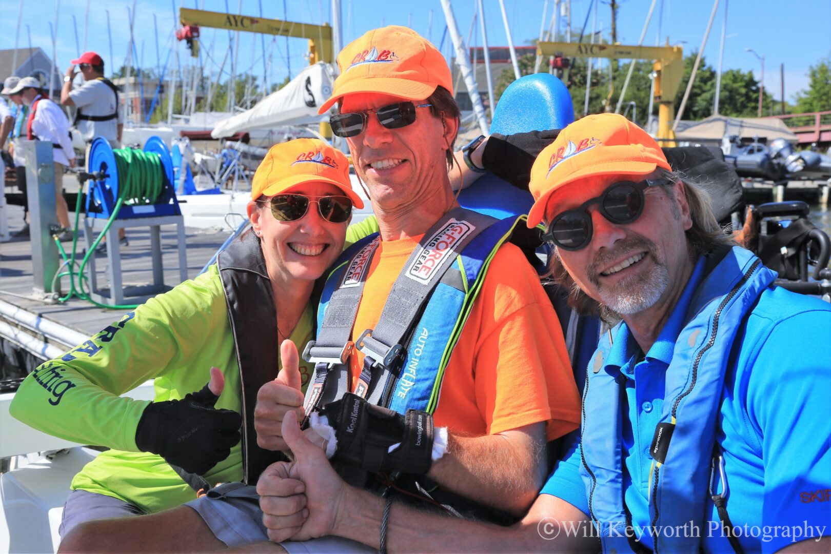 A photo of two volunteers and a guest in dock on a CRAB sailboat preparing to sail. 