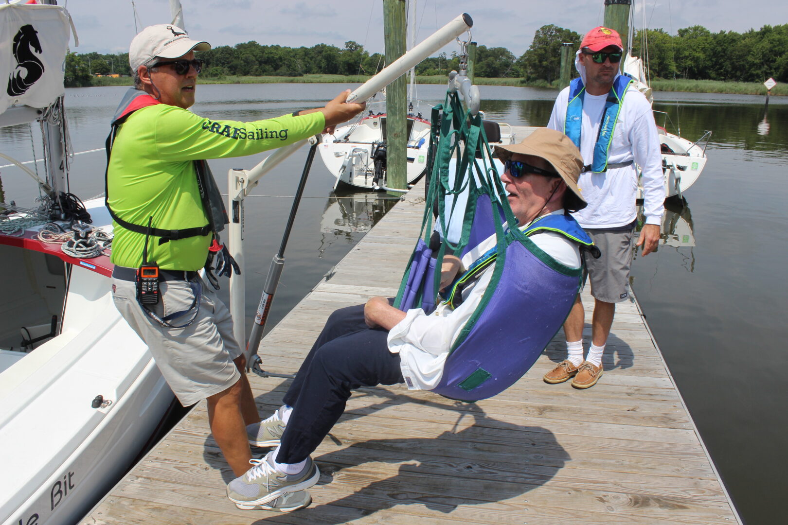 Photo on CRAB dock of a guest being transferred to a CRAB sailboat using the Aqua lift, formerly called a Hoyer lift. 