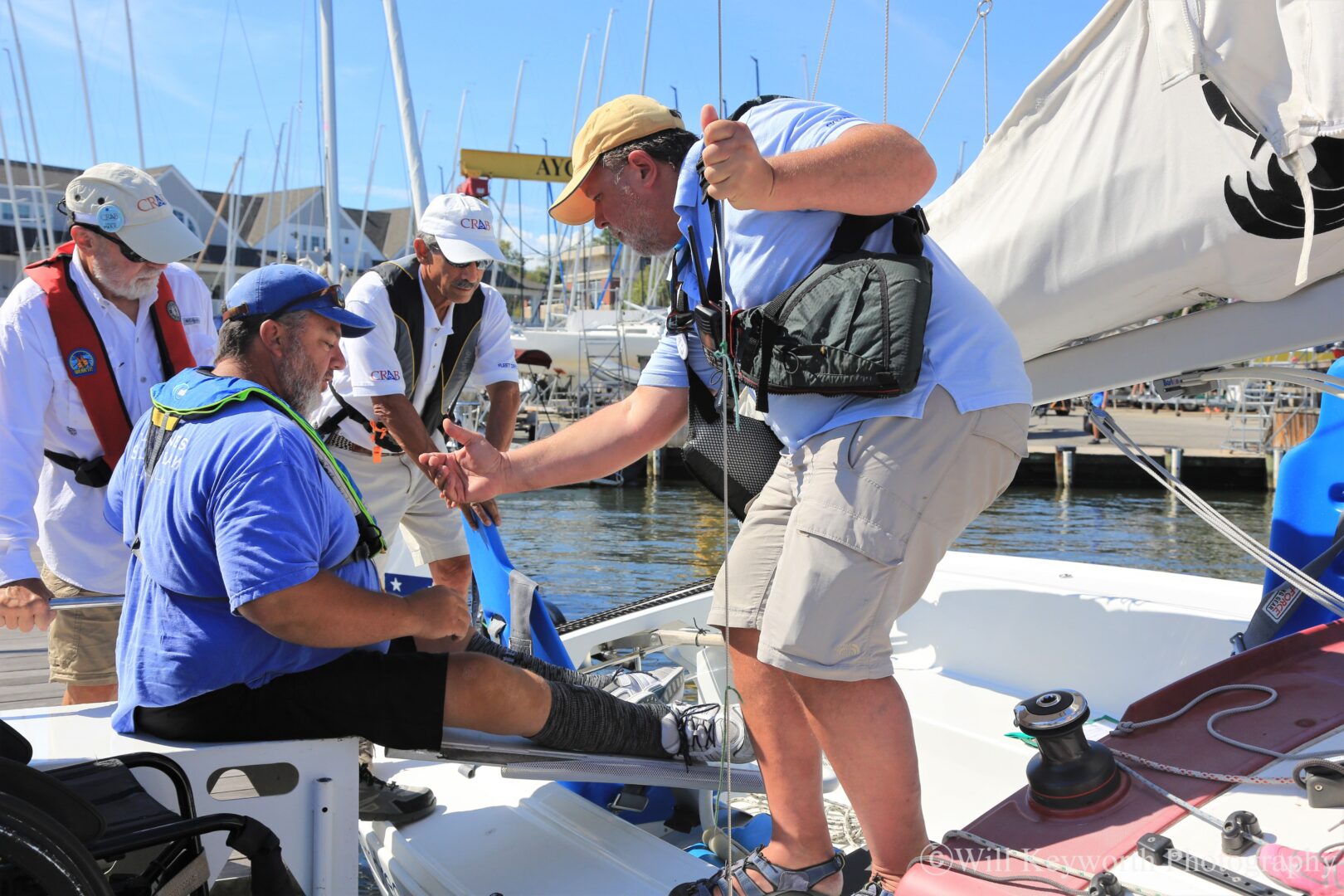 Photo of CRAB volunteers helping a CRAB guest safely access a CRAB sailboat. 