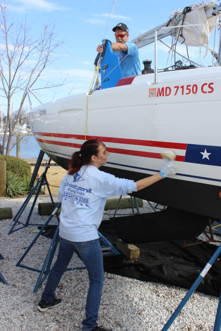 Photo of two CRAB volunteers cleaning a CRAB sailboat and getting it ready for the sailing season. 