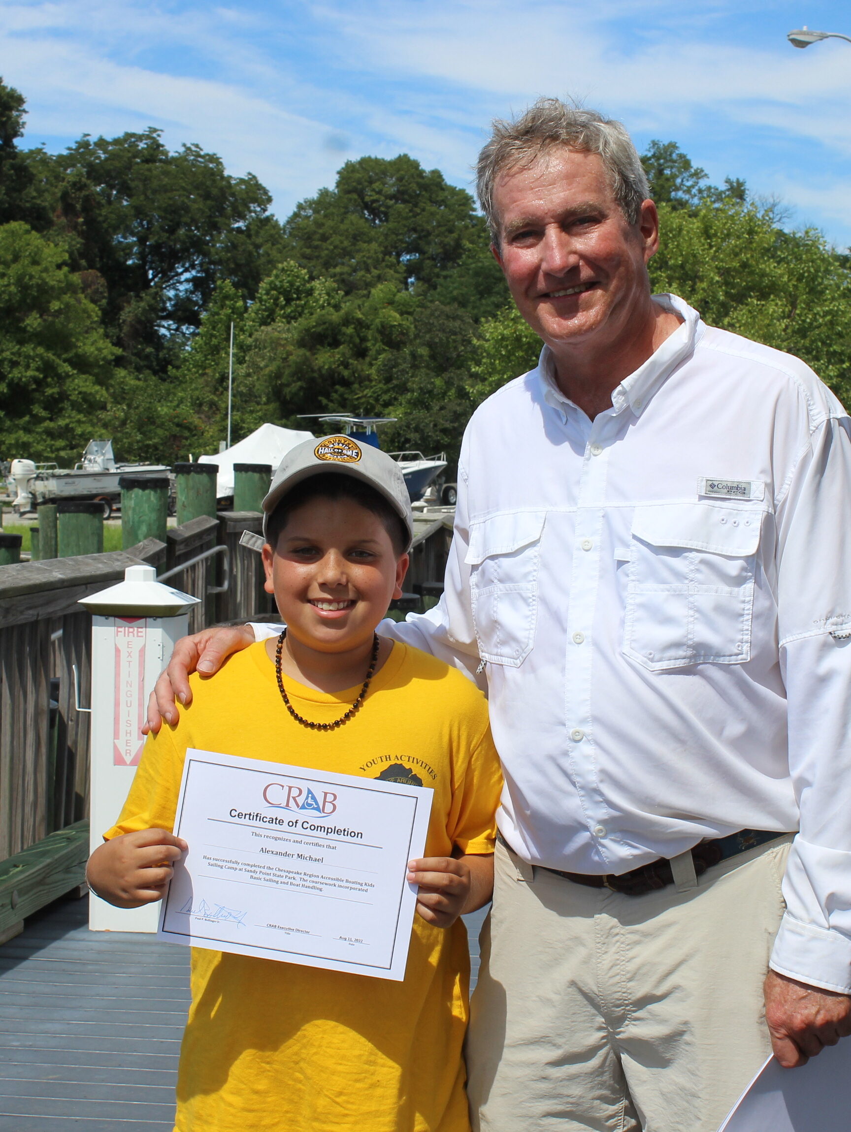 A young CRAB guest holding a CRAB certificate standing next to CRAB President and CEO, Paul Bollinger. 