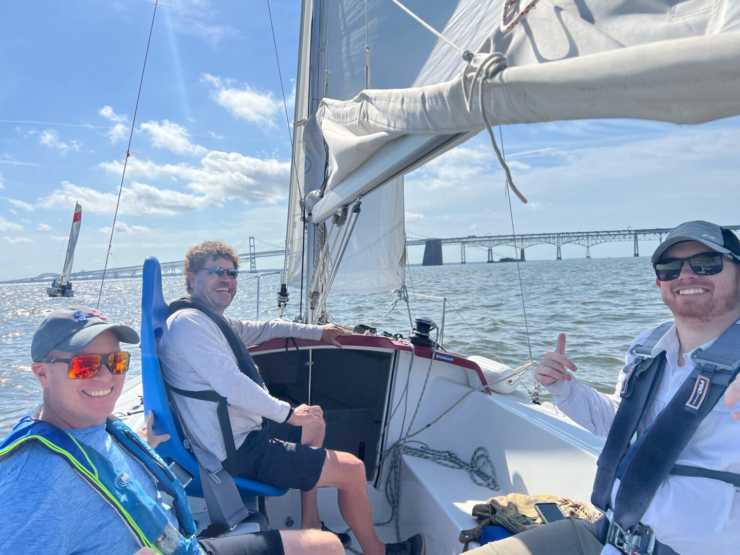 Photo of 3 CRAB volunteers and participants in one of CRAB's sailboats on the water competing and enjoying the regatta.  